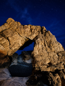 Starlit rock arch in desert night